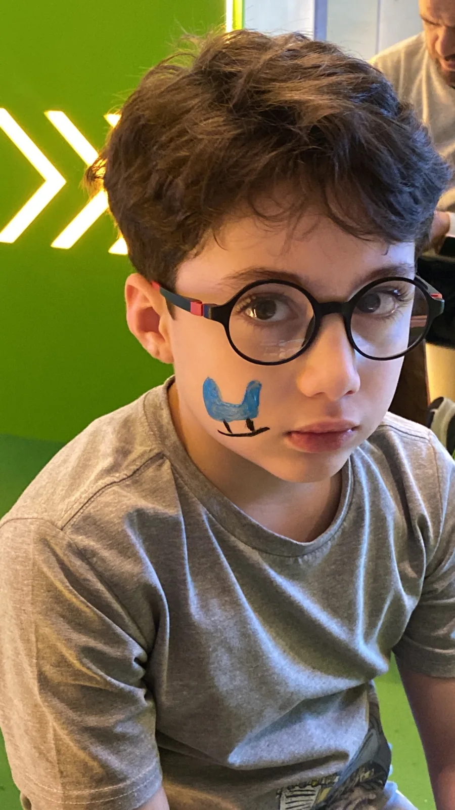 Young participant with painted cheek at the family activity area.