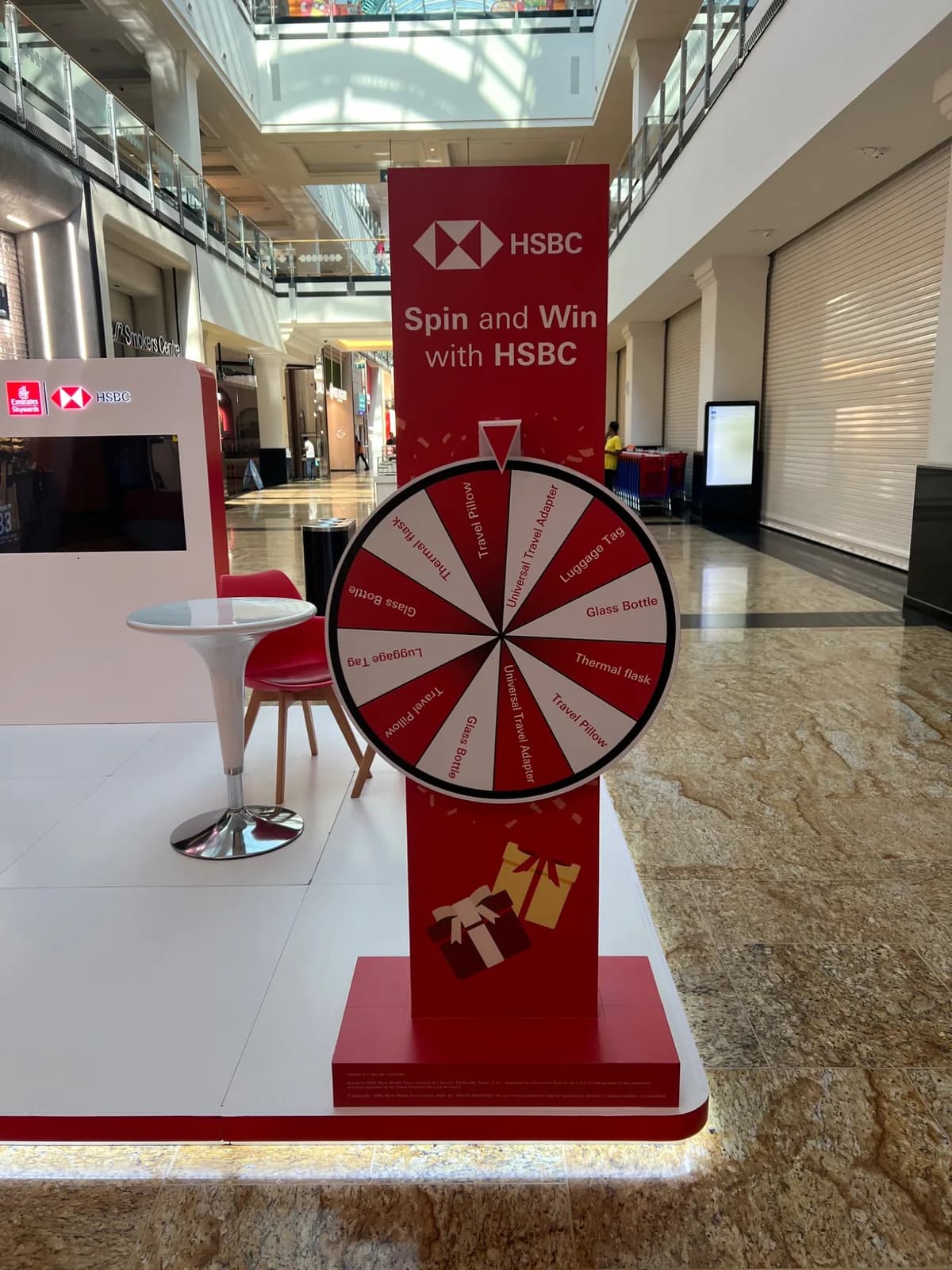 HSBC Spin and Win wheel with red signage, white platform and adjacent seating.
