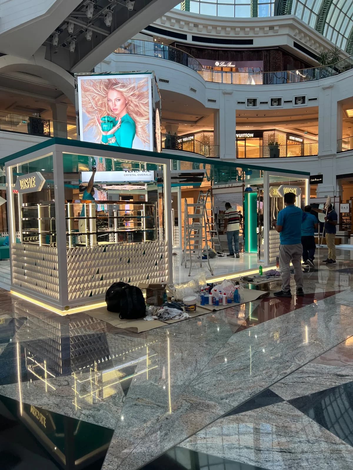 Wide view of the Versace kiosk in a mall atrium during installation.